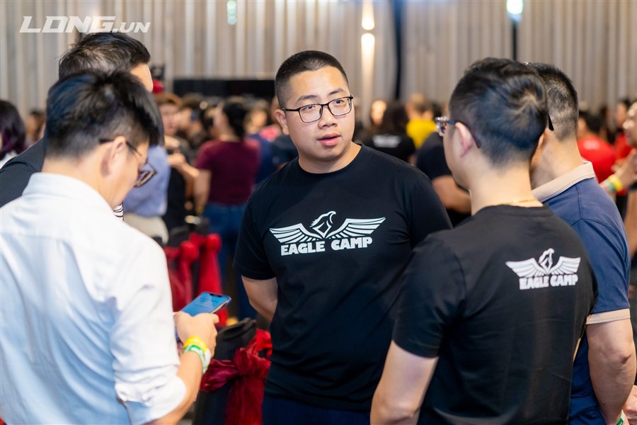 Anh Trần Trọng Trường mặc áo Eagle Camp trò chuyện tại một sự kiện của cộng đồng thầy Phạm Thành Long